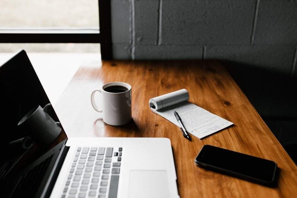 Bureau avec un ordinateur, une tasse de café, un smartphone, un stylo et un carnet